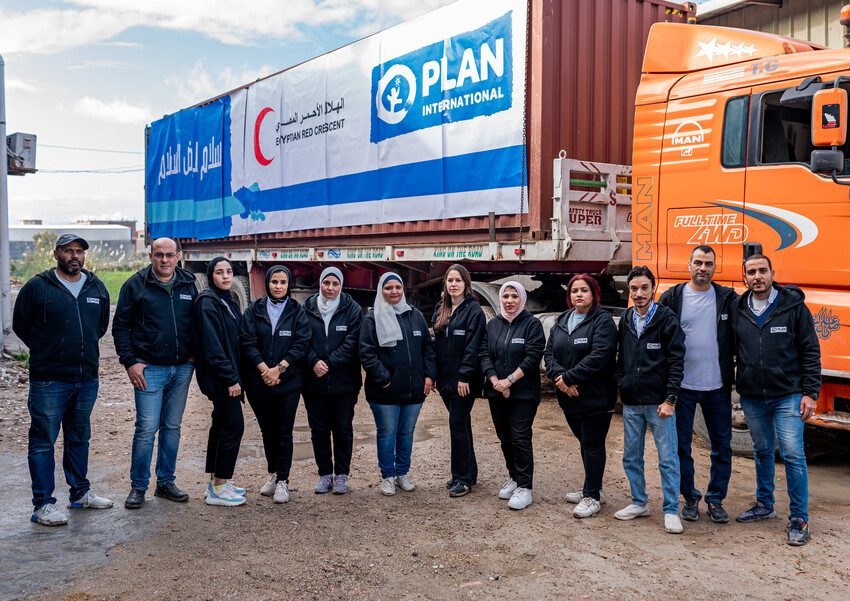 Plan Egypt staff stand in front of a truck loaded with relief supplies for Gaza.